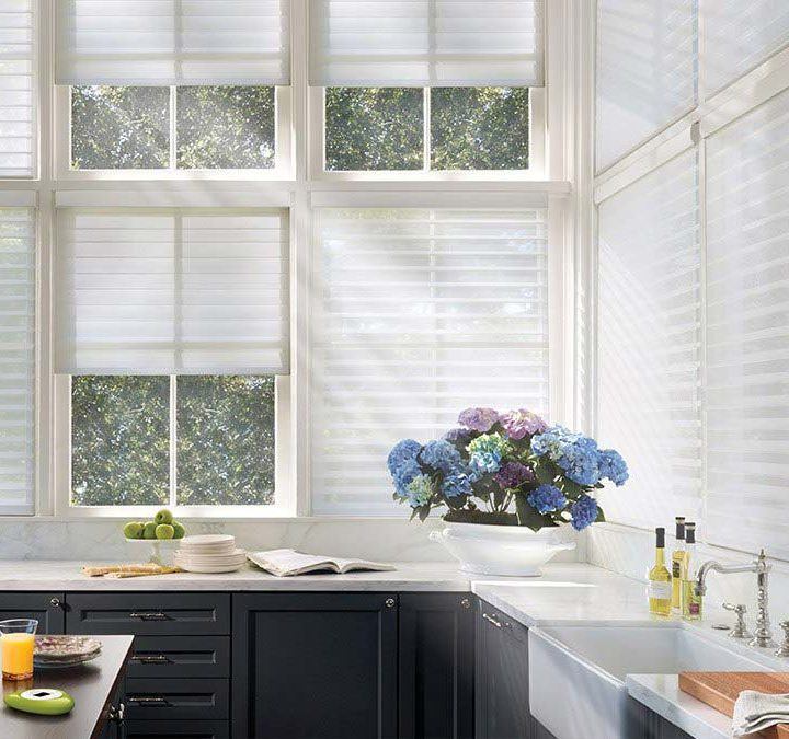 a kitchen with large windows that have Hunter Douglas motorized white blinds
