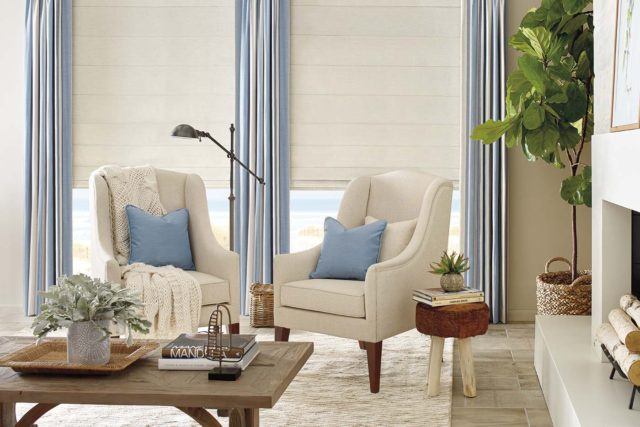 wooden coffee table with two white arm chairs and blue accent pillows