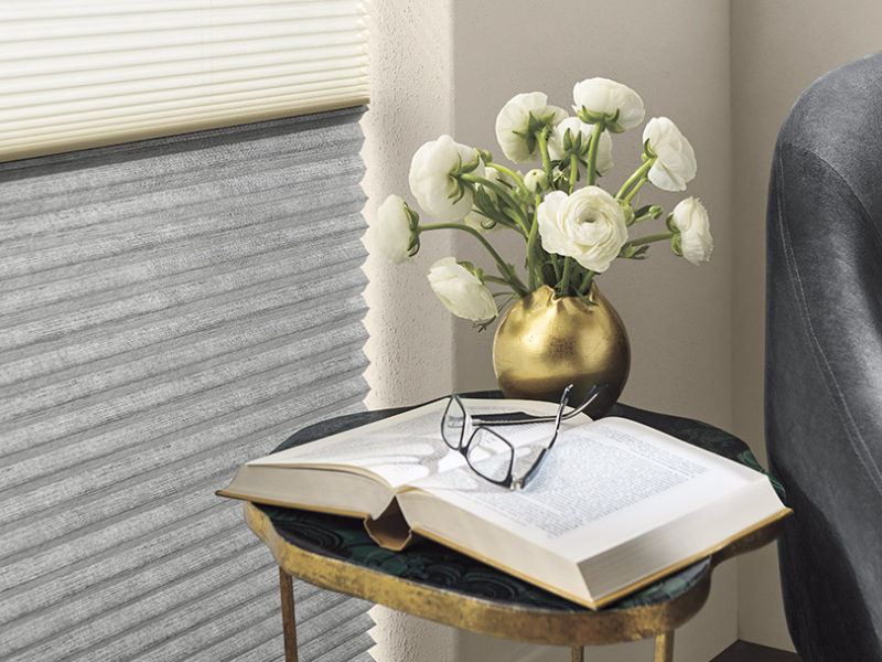 Hunter Douglas cellular shades being featured next to an open book with glasses