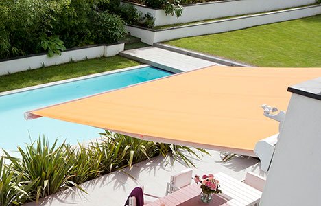 a retractable yellow awning covering a patio in a backyard with a pool