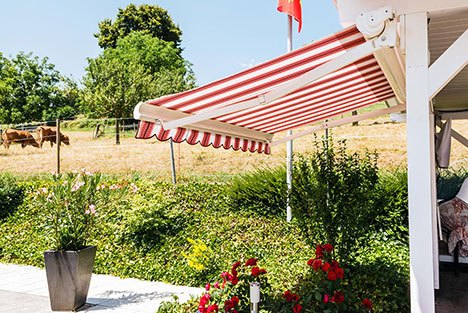 a patio with a retractable red striped awning