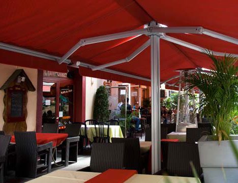 a restaurant patio being covered by large, red, stand alone awnings