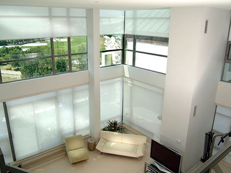 A large living room with high ceilings featuring motorized blinds