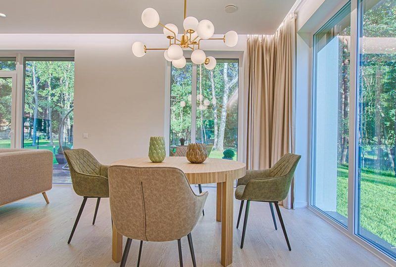 a dining room table with four arm chairs, with floor length drapery in the background