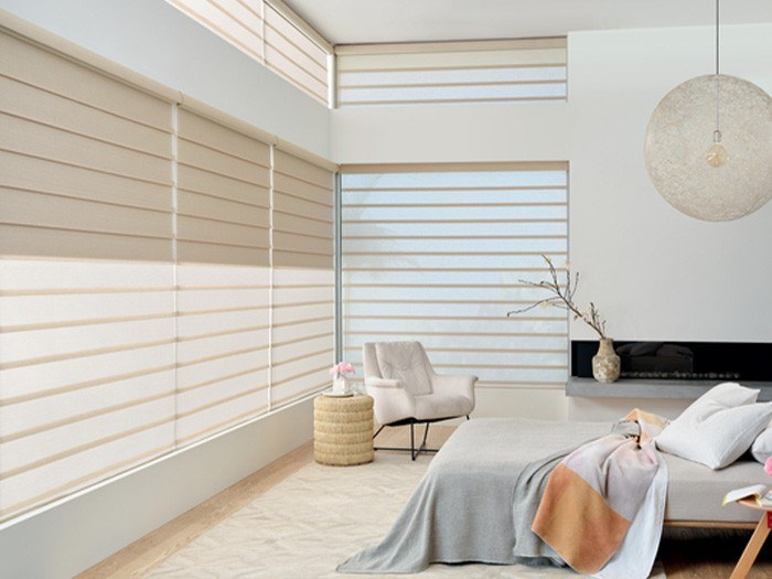 a bedroom with a bed, chair, and window with shades and blinds