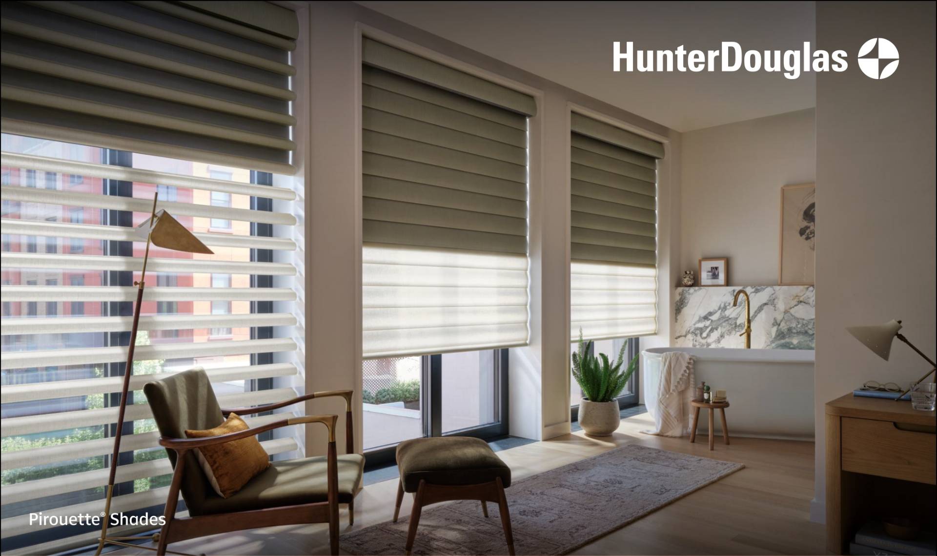 Hunter Douglas Pirouette shades installed on large windows in a sunlit room featuring an armchair, ottoman, and freestanding bathtub.